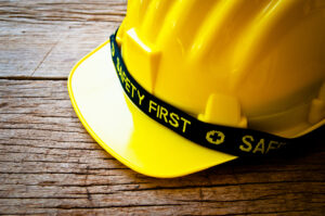 Worker Yellow Safety Helmet Hat with SAFETY FIRST word tag on Wood background